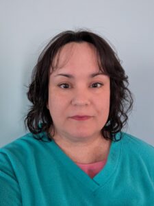 Person wearing teal top against plain background.